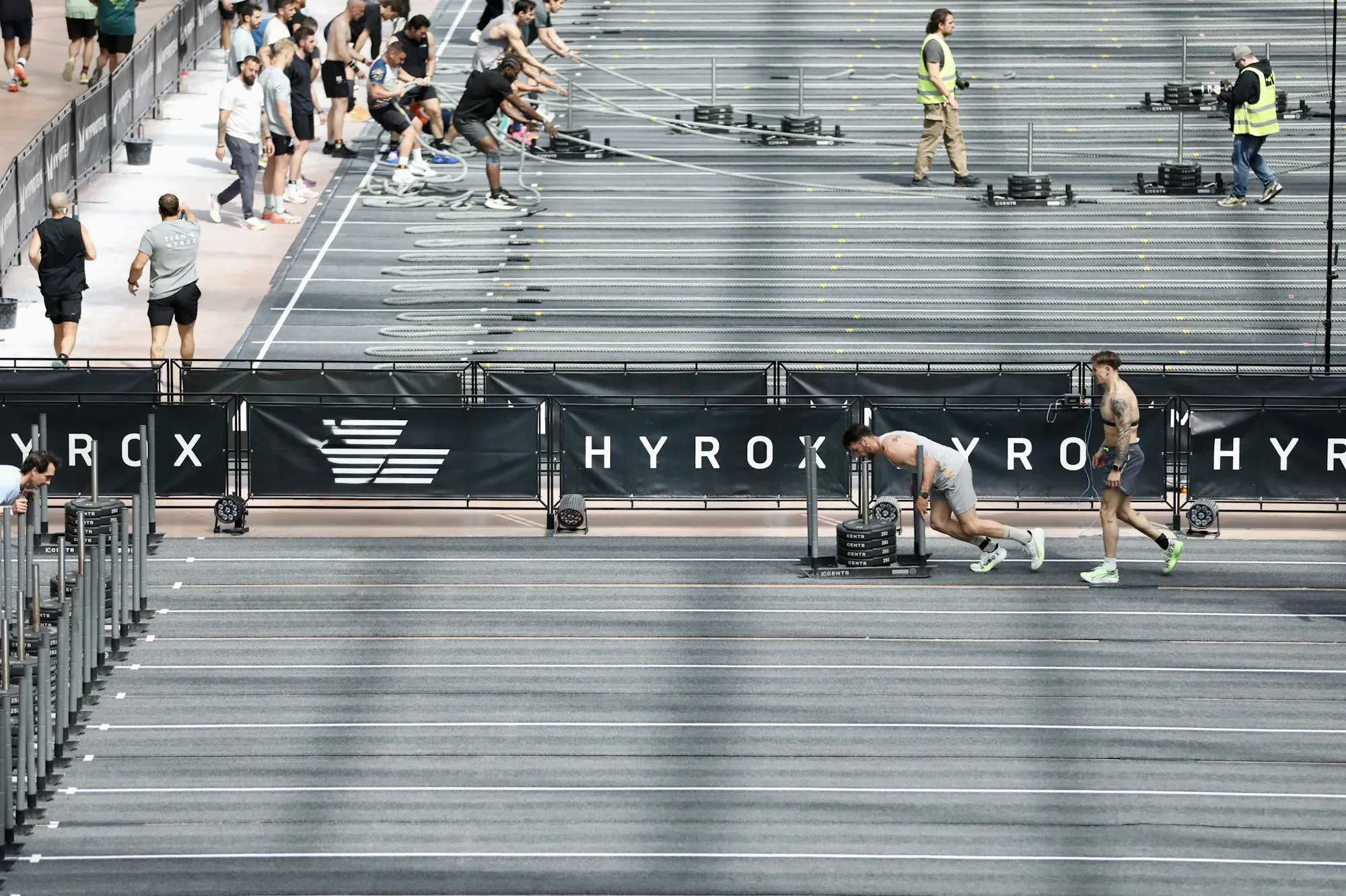 Учасники перегонів HYROX штовхають сани на доріжці